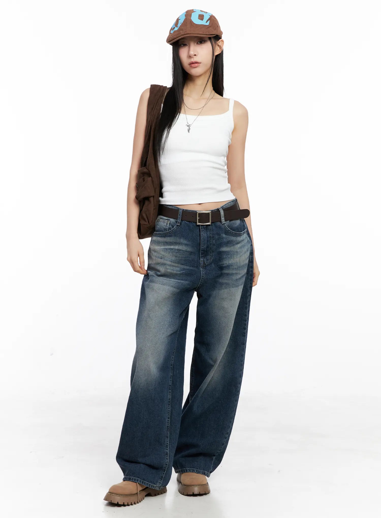 LEWKIN Aisha Washed Baggy Jeans CC1109 in mid blue, full-length front shot on model, wide-fit cotton denim with washed finish, styled with white tank, brown jacket, and chunky boots.