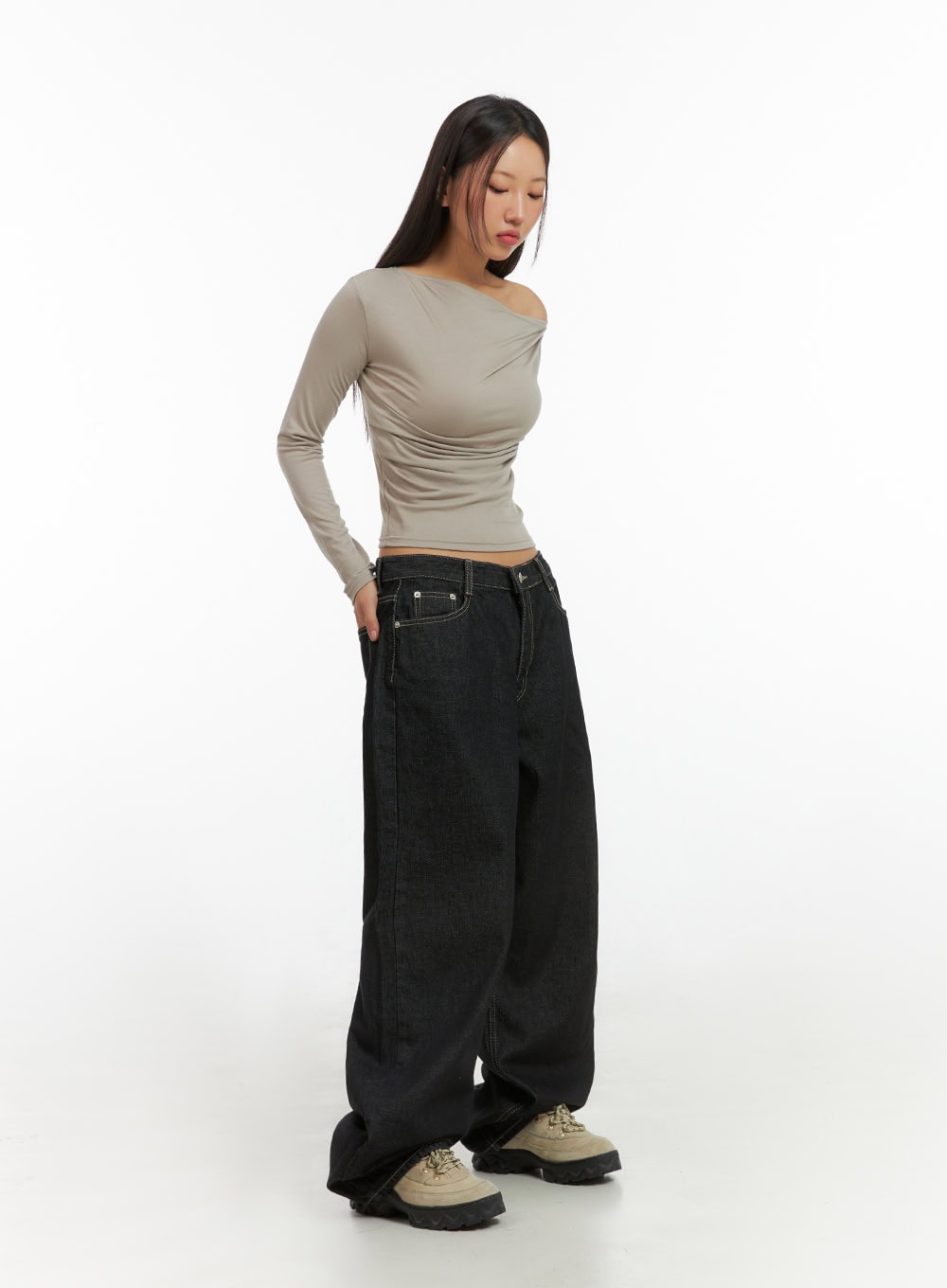 LEWKIN Clover Stitched Baggy Jeans IS402 in black, 3/4 side view on model, wide-fit low-rise cotton denim with contrast stitching, pooling at hem, styled with beige asymmetric top and chunky boots.