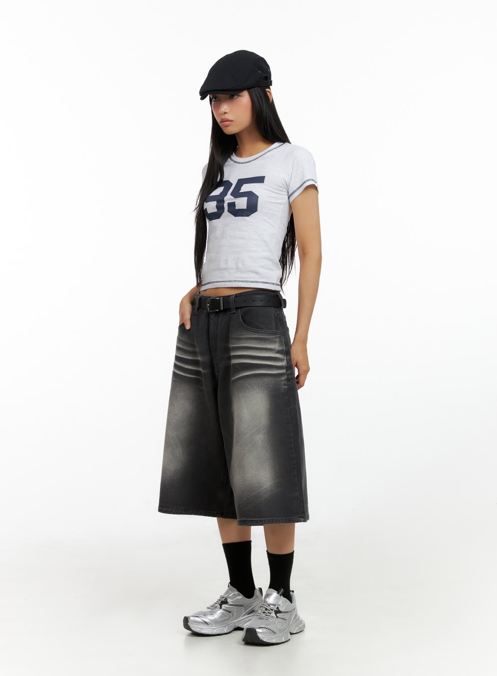 LEWKIN Washed Baggy Jorts IL419 in black, 3/4 angled full-body on model, wide-fit midi denim with washed fade, belted waist, styled with crop tee and silver sneakers.