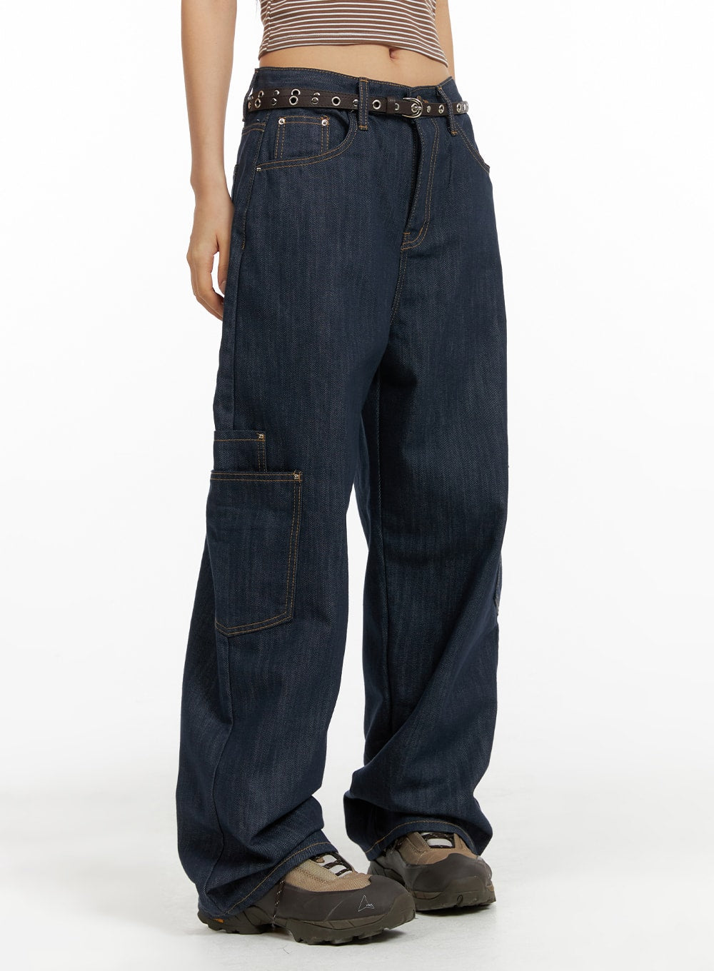 LEWKIN Pocketed Denim Wide Leg Jeans CF423 in dark blue, angled front view on model, low-waist wide fit cotton denim with contrast stitching, cargo pocket, eyelet belt, styled with chunky sneakers.