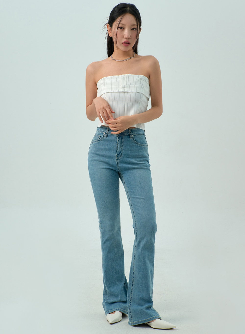 LEWKIN Light Wash Bootcut Jeans CY330 in light blue, full front view on model, slim-fit high-rise washed denim with flared hem, paired with white strapless top and white heels.