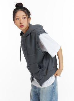LEWKIN Two-Way Zip Hoodie Vest CF419 in charcoal grey, angled side view on model, cotton fleece sleeveless hoodie with zip closure, layered over white tee and light blue jeans.