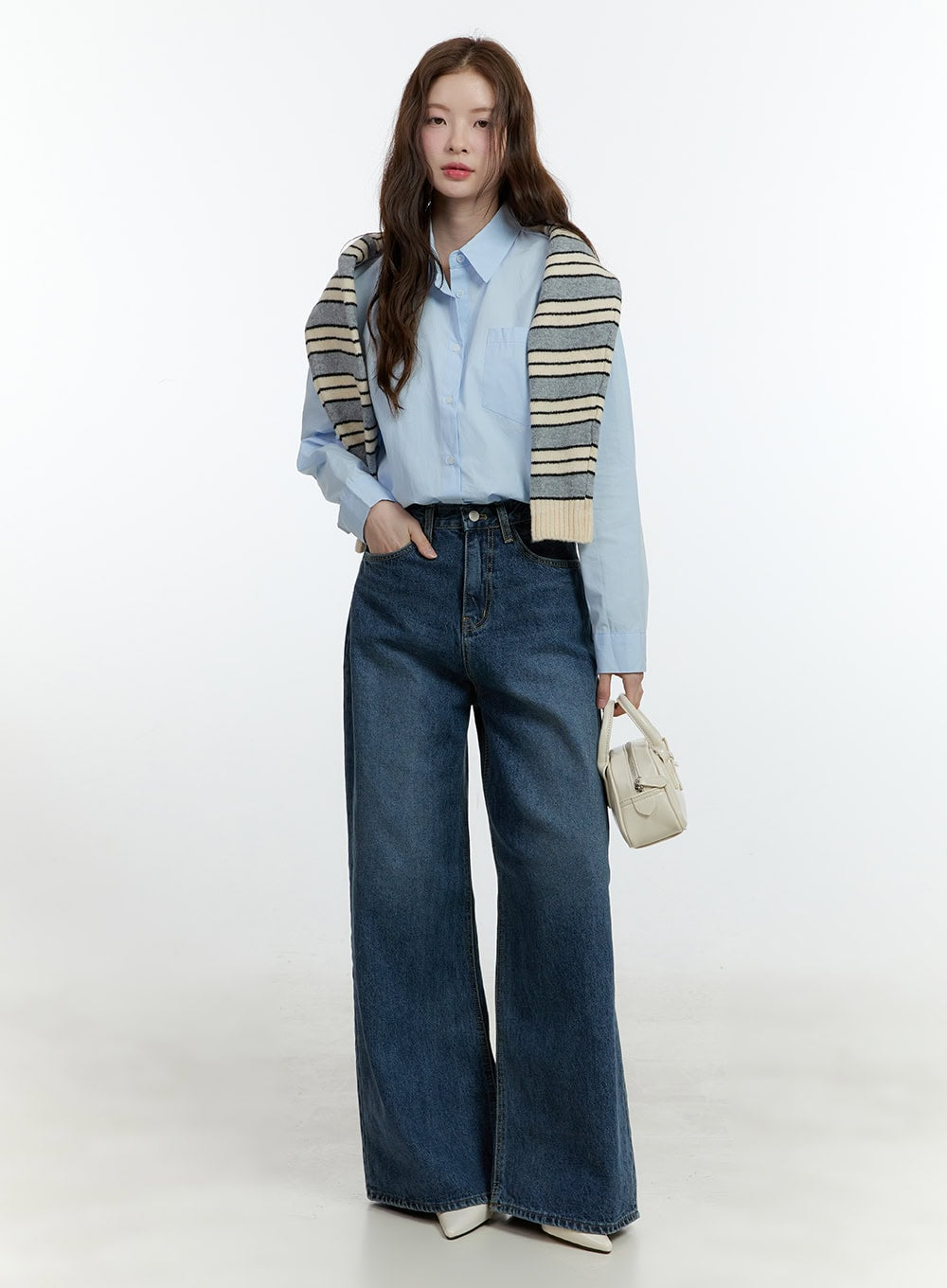Klaudia Wide-Leg Jeans CF503 in blue, full-length front shot on model, wide-fit washed denim, styled with light blue shirt and striped knit draped over shoulders, cream mini bag.