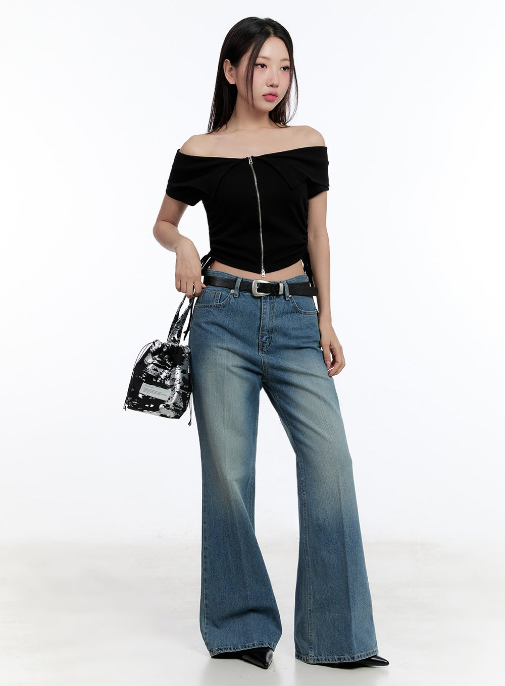 LEWKIN Aliya Washed Bootcut Jeans IU503 in dark blue, full-body front shot on model, wide-fit washed denim with bootcut flare, belted and paired with black off-shoulder crop top and mini bag.