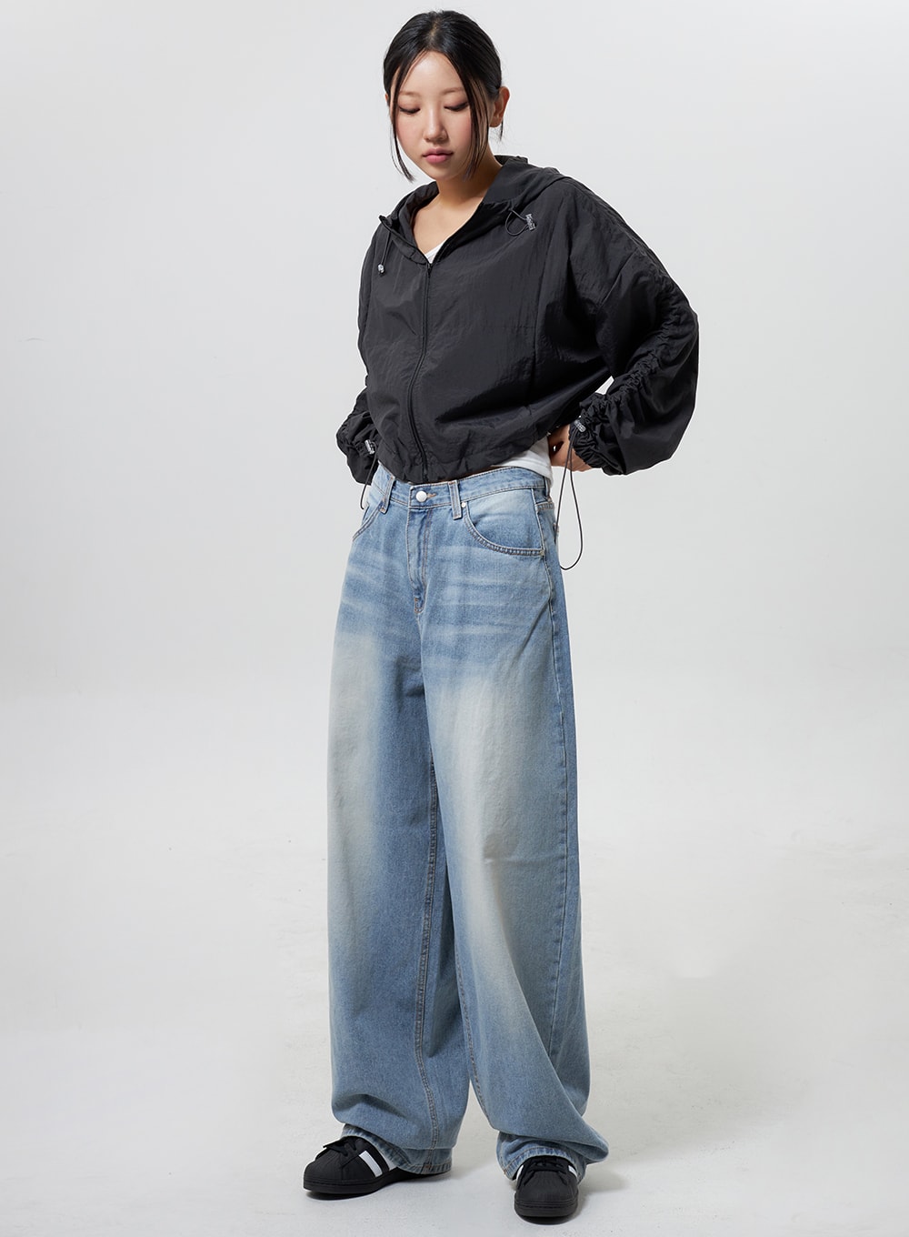 LEWKIN Low Rise Baggy Jeans CY324 in light blue, full-length front view on model, wide-leg cotton denim with faded wash, paired with black cropped windbreaker and sneakers.