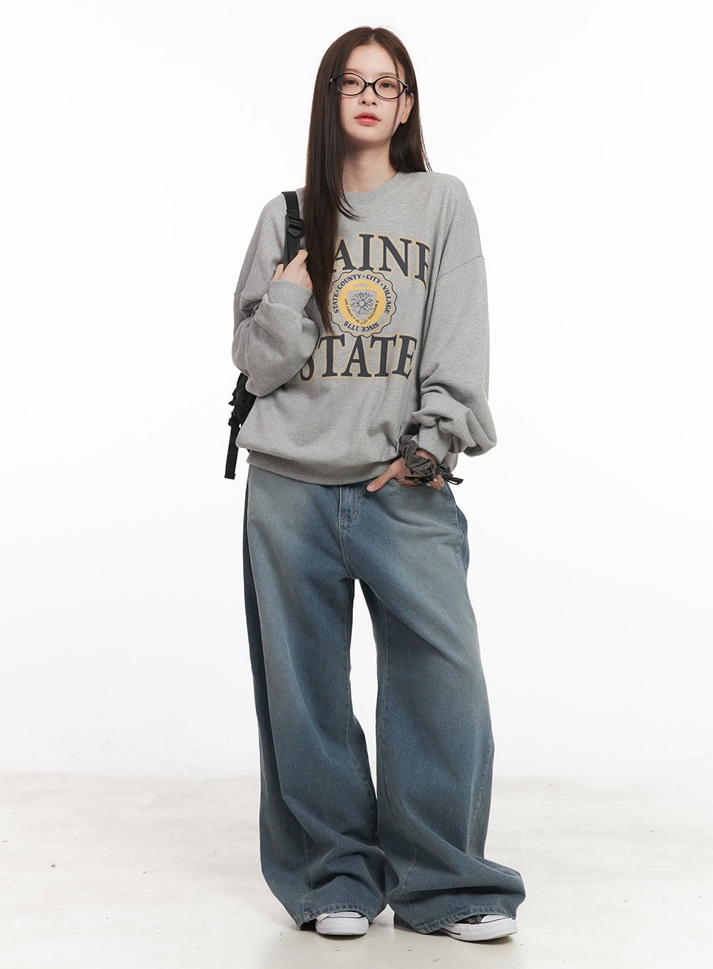 Amber Pintuck Wide-Leg Jeans CM511 in blue, full-body front on model, wide-fit washed denim styled with oversized grey graphic sweatshirt and backpack.