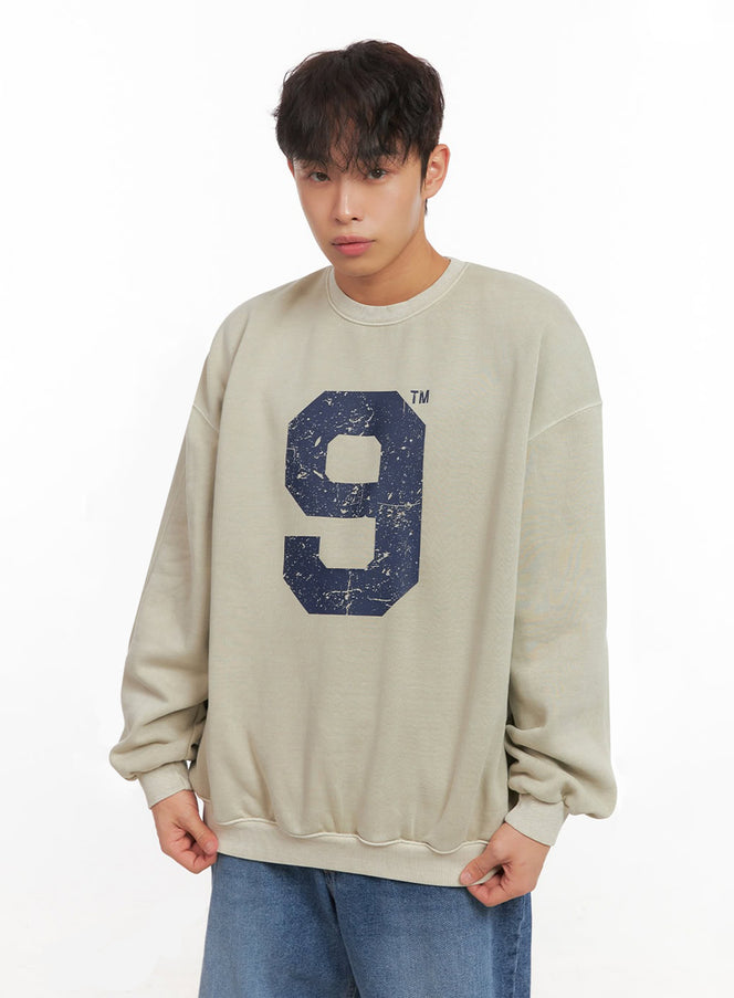 LEWKIN Men's Casual Long-Sleeve Oversized Tee ID427 in beige, front close-up on model, drop-shoulder crewneck sweatshirt with distressed navy number 9 graphic print, ribbed cuffs, paired with blue jeans.