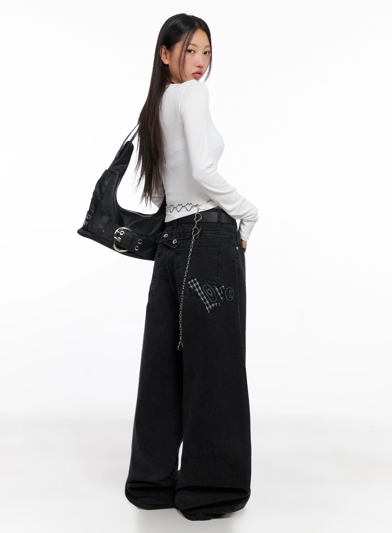 LEWKIN Sunwoo Embroidered Wide Leg Jeans IG528 in black, rear three-quarter view on model, loose cotton denim with gingham patch 'love' embroidery on back pocket, styled with white top and black shoulder bag.
