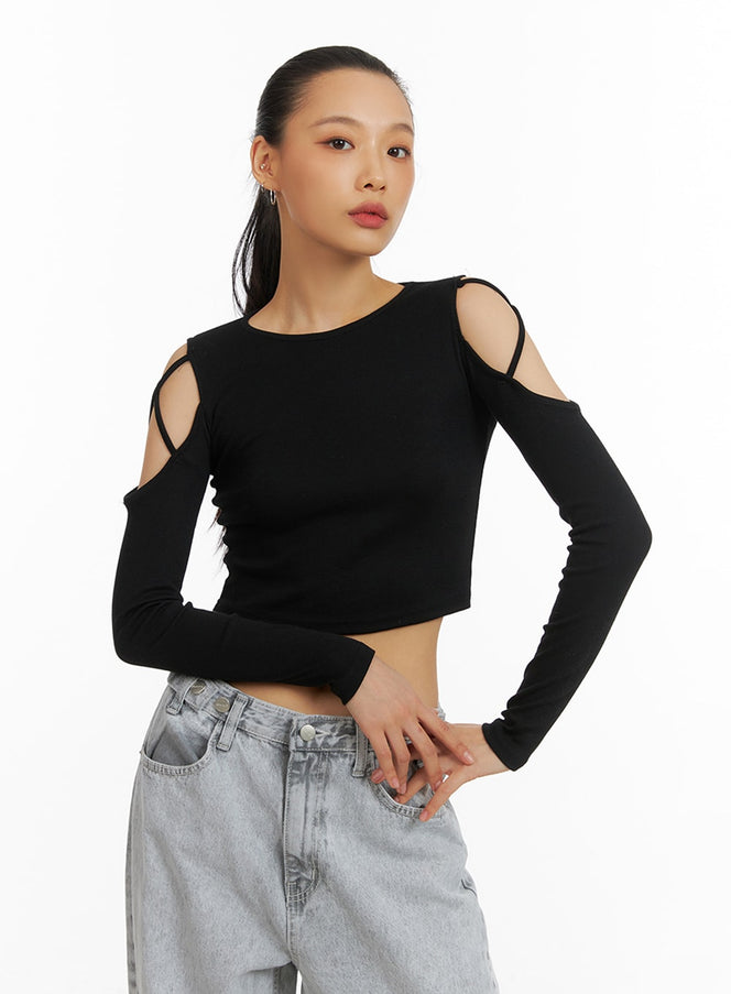 LEWKIN X-Strap Cut-Out Crop Top IA417 in black, angled front view on model, slim-fit long sleeve with cold-shoulder X-strap cut-outs, paired with light grey wide-leg jeans.