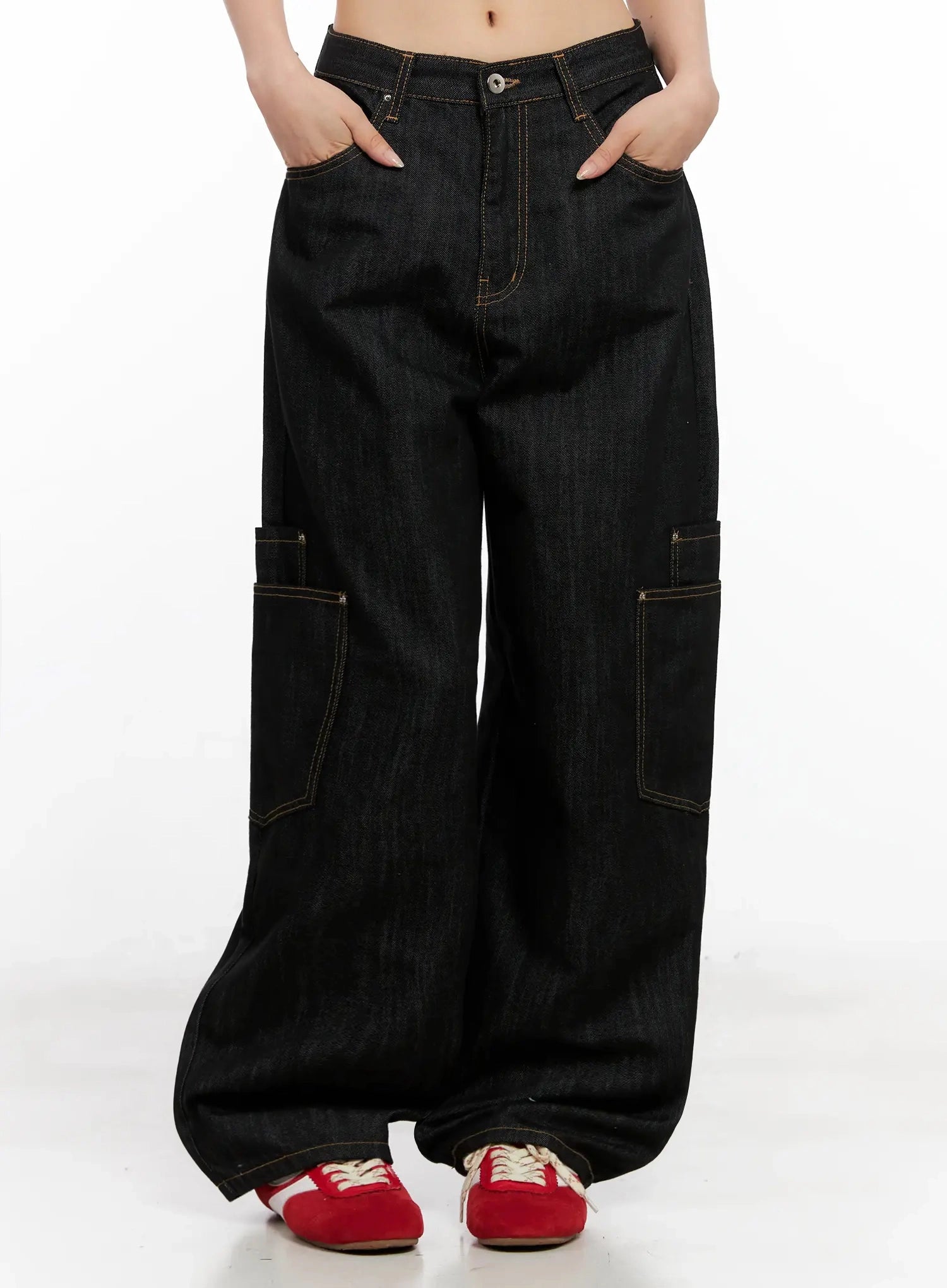 LEWKIN Dahee Wide-Leg Cargo Jeans IG508 in black, front close-up on model, hands in pockets, wide-fit cotton denim with contrast topstitching and side cargo pockets, paired with red sneakers.