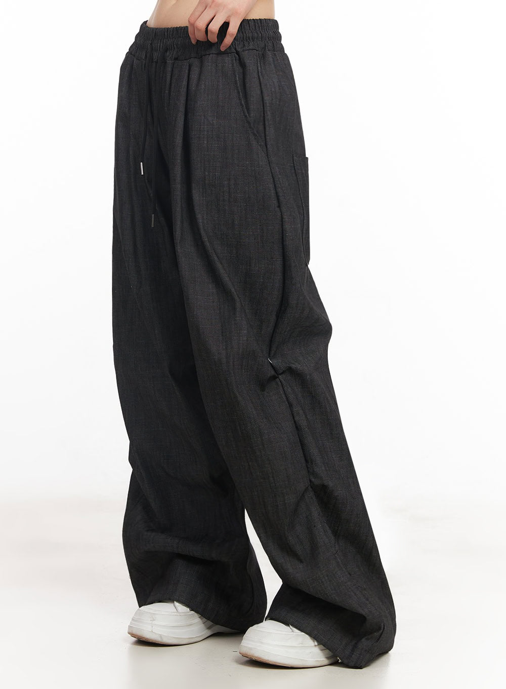 LEWKIN Pintuck Denim Sweatpants IY529 in black, side view on model, wide-fit cotton denim with elastic banded waist, pintuck front crease, drawstring, and side pocket, styled with white sneakers.