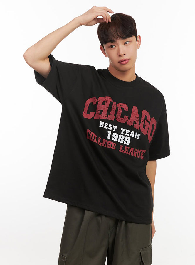 LEWKIN Men's Graphic T-Shirt IF521 in Black, angled front close-up on model, oversized fit with distressed Chicago college league print, paired with olive cargo pants.
