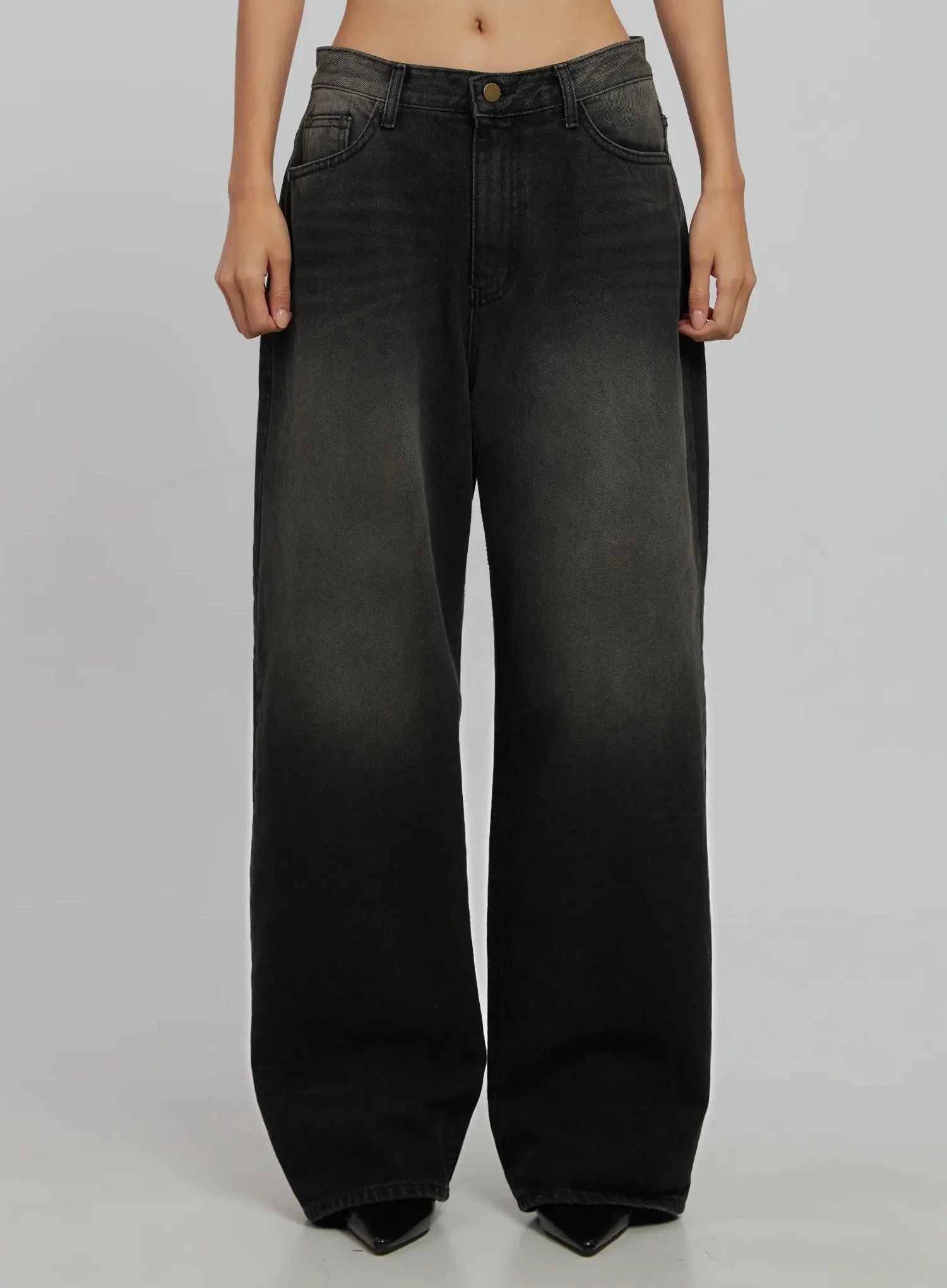 LEWKIN Blaire Dark Washed Wide Leg Jeans IJ509 in black, front product shot on model, low-rise waistband with brass button, wide cotton denim legs with faded wash, paired with black heels.