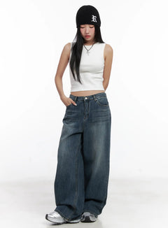 LEWKIN Aya Washed Baggy Jeans CN528 in blue, full-length front shot on model wearing white crop tank and black beanie, wide-leg cotton denim with washed finish, paired with silver sneakers.