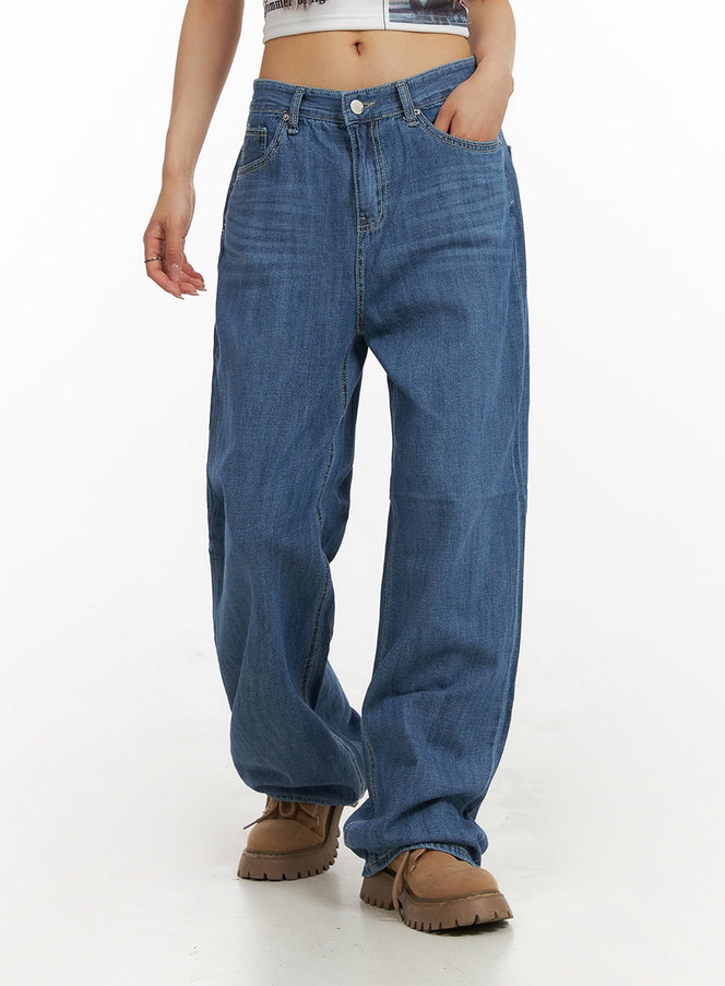 LEWKIN Solid Low Rise Baggy Jeans CY407 in blue, front cropped shot on model, low-rise waistband and wide-leg silhouette, washed denim, paired with white graphic crop top and tan chunky boots.