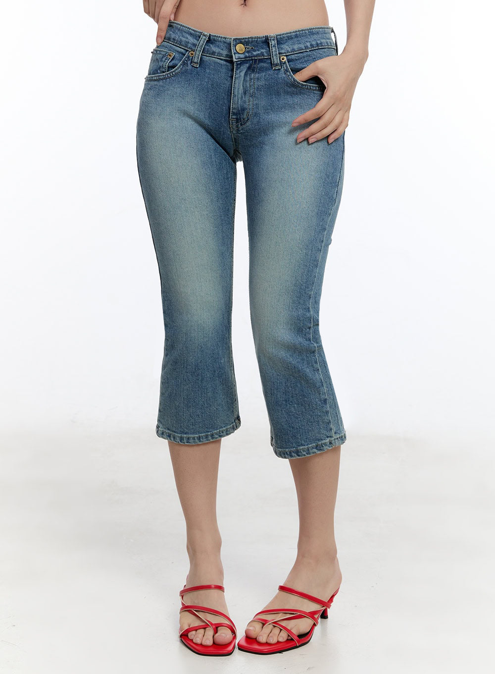 LEWKIN Kyra Cropped Low-Rise Skinny Jeans IU503 in blue, front close-up on model, washed denim, low-rise waist with gold button, cropped length, paired with red strappy heeled mules.