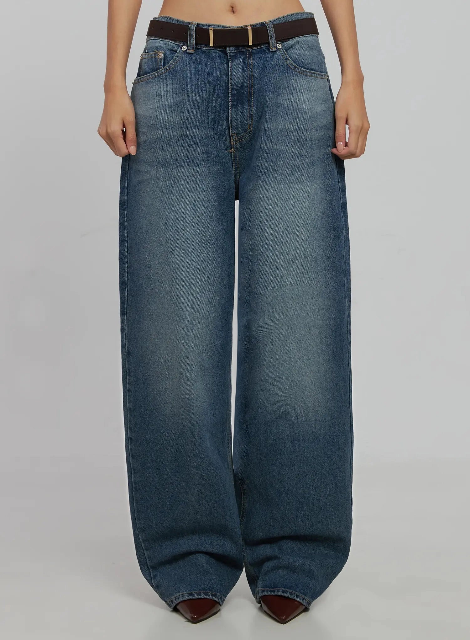 LEWKIN Akira Wide Leg Jeans IJ508 in blue, front crop view on model, washed cotton wide-fit with low rise, paired with brown leather belt and burgundy pointed boots.