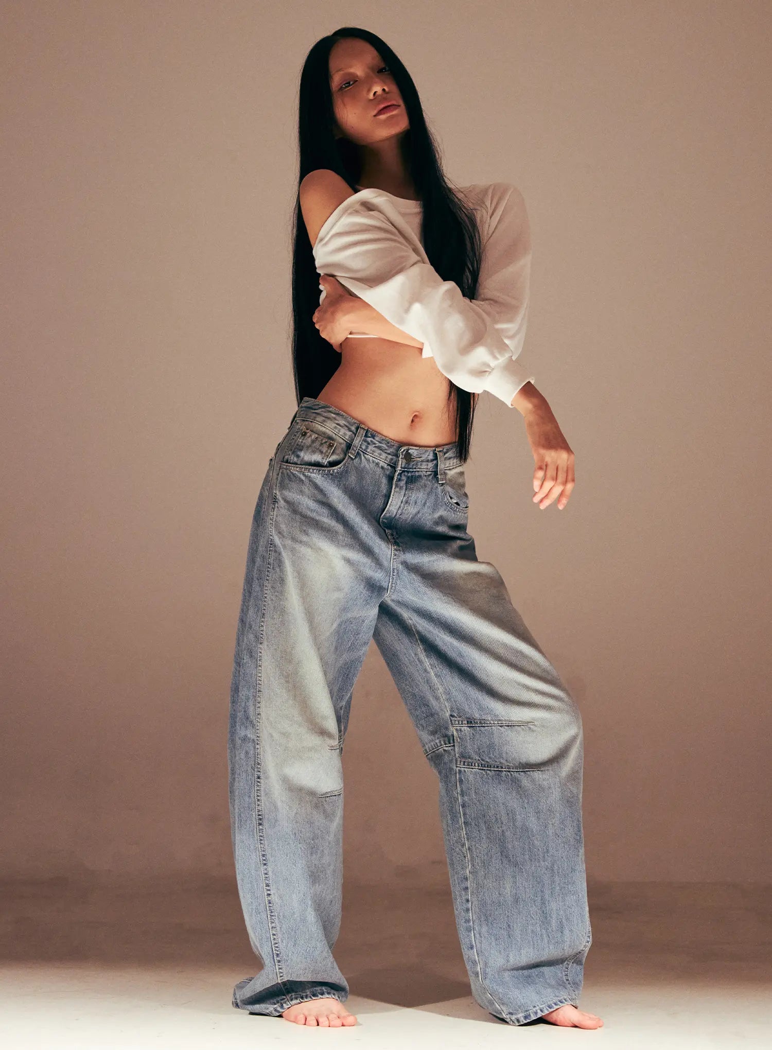 LEWKIN Dakota Relaxed Fit Vintage Wash Jeans CS511 in blue, full-length editorial shot on model, relaxed wide-leg cotton denim with vintage wash, low-rise waist, paired with white off-shoulder crop top, barefoot.