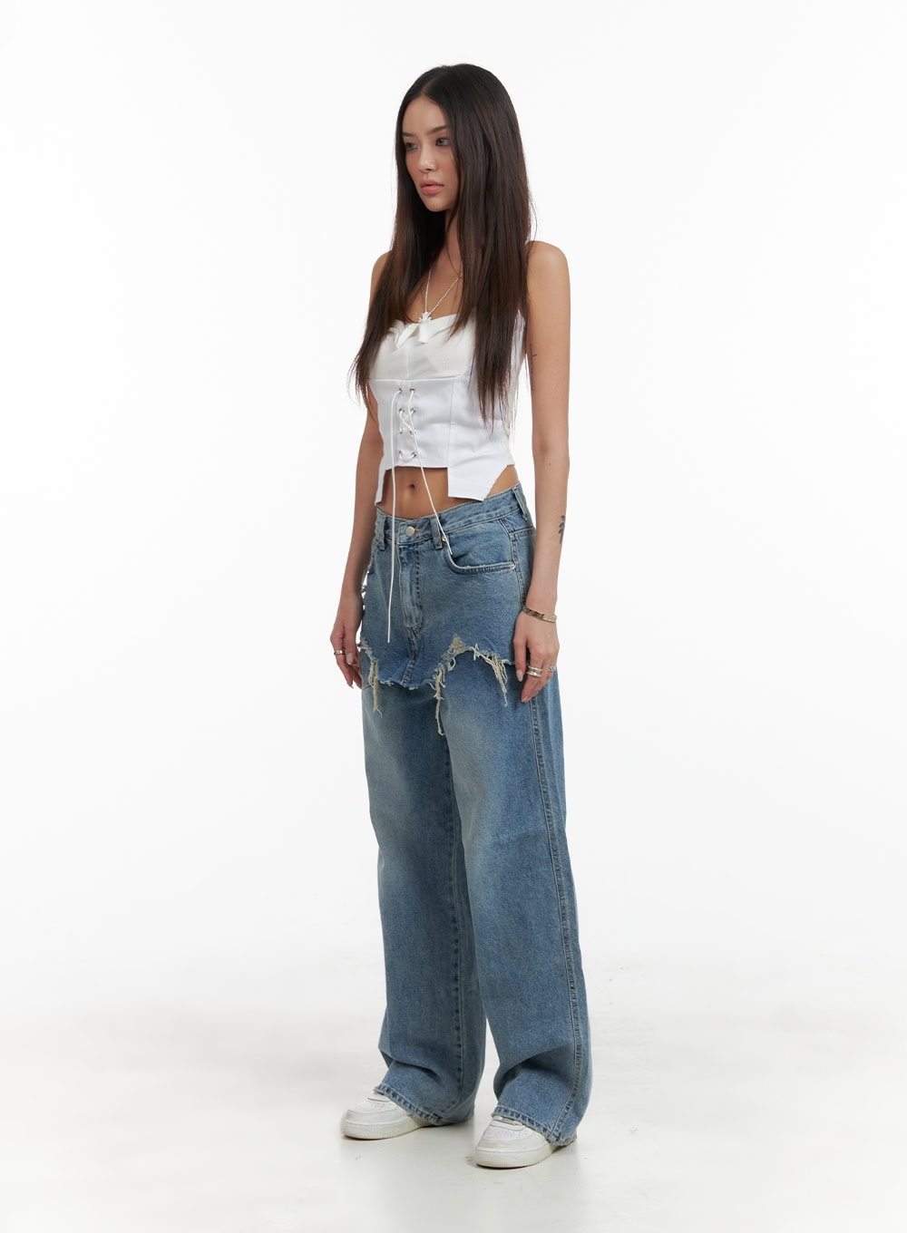 LEWKIN Layered Wide Leg Jeans CA430 in Blue, full-length front-angle view on model, washed cotton denim with destroyed frayed layered skirt overlay, wide fit, styled with white lace-up corset crop top and white sneakers.