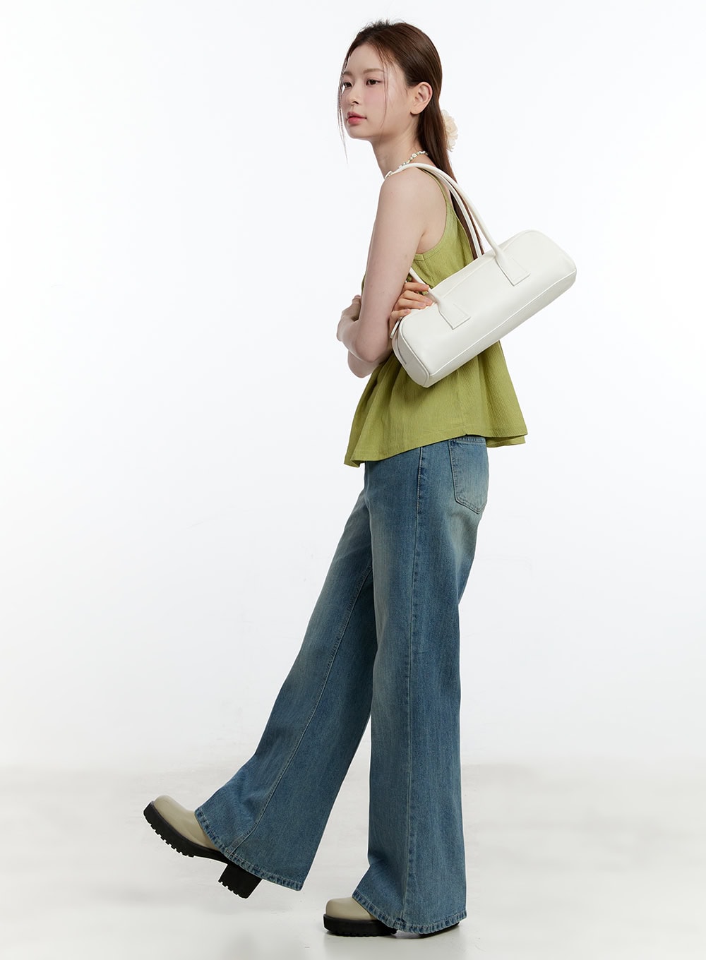 LEWKIN Aleks Relaxed-Fit Flared Jeans CM521 in blue (3XL), side view on model walking, wide-fit washed denim with flared hem, styled with green cami top and white shoulder bag.