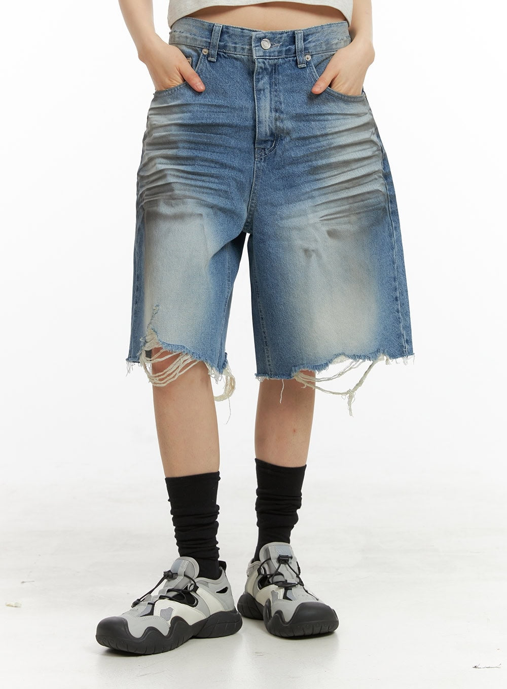 LEWKIN Destroyed Hem Bermuda Jorts CY414 in blue, front waist-down close-up on model, wide-fit washed denim with heavy fray hem, hands in pockets, styled with black socks and chunky sneakers.