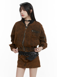 LEWKIN Stand Collar Solid Denim Jacket CA402 in Brown, front three-quarter view on model, washed cotton crop bomber with zip-up front, chest zip pocket, elastic hem, styled with matching denim mini skirt and black belt bag.