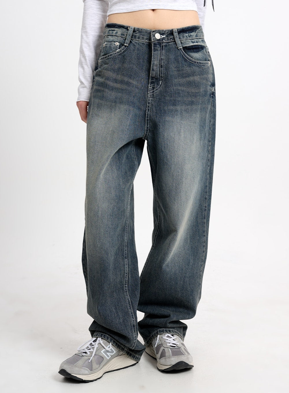 LEWKIN Low Waist Baggy Jeans CM415 in dark blue, front mid-shot on model, wide-fit washed denim with faded whisker details, paired with white crop top and grey sneakers.