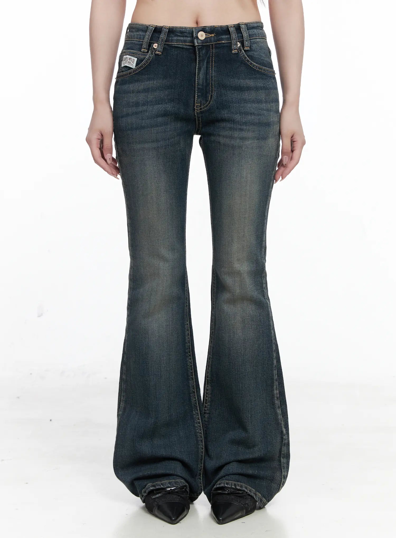 LEWKIN Rosé Washed Bootcut Jeans CO520 in dark blue, front crop view on model, low-rise waist with gold button, washed cotton-spandex flare leg, paired with black pointed boots.