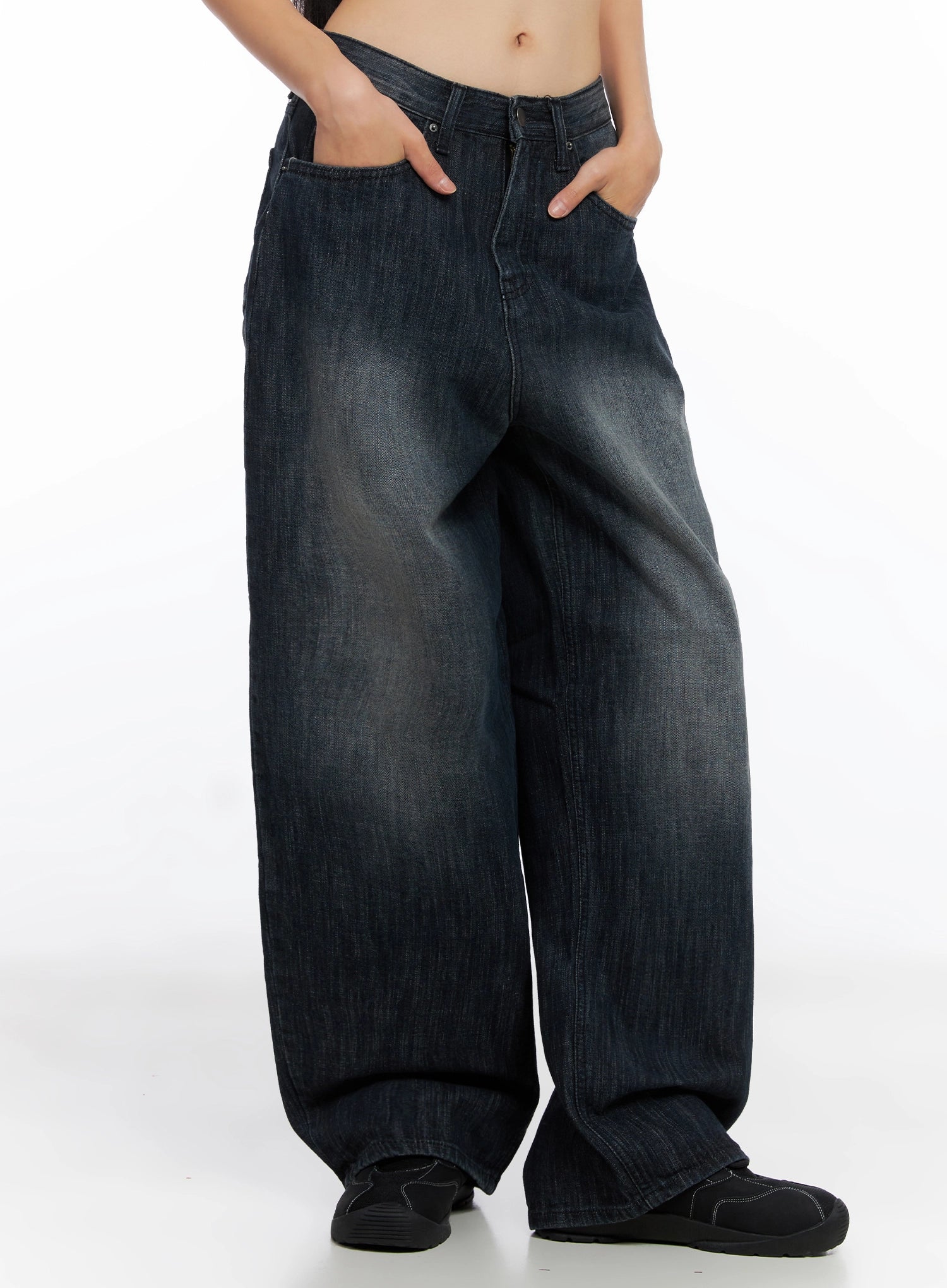 LEWKIN Minnell Vintage-Wash Wide-Leg Jeans IO517 in dark blue, angled front view on model, hands in pockets, loose baggy cotton denim with vintage wash, paired with black sneakers.