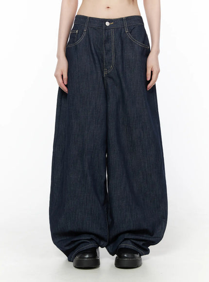 Rowen Baggy Jeans CU519 in dark blue, front view on model, ultra-wide balloon leg silhouette with contrast stitching and button waist, pooling at hem, paired with black leather shoes.