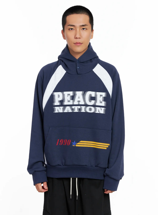 LEWKIN Men's Raglan Graphic High Neck Hoodie IS510 in dark blue, front crop shot on model, oversized fleece with white raglan panels, snap-button high neck, PEACE NATION graphic print, paired with black drawstring pants.