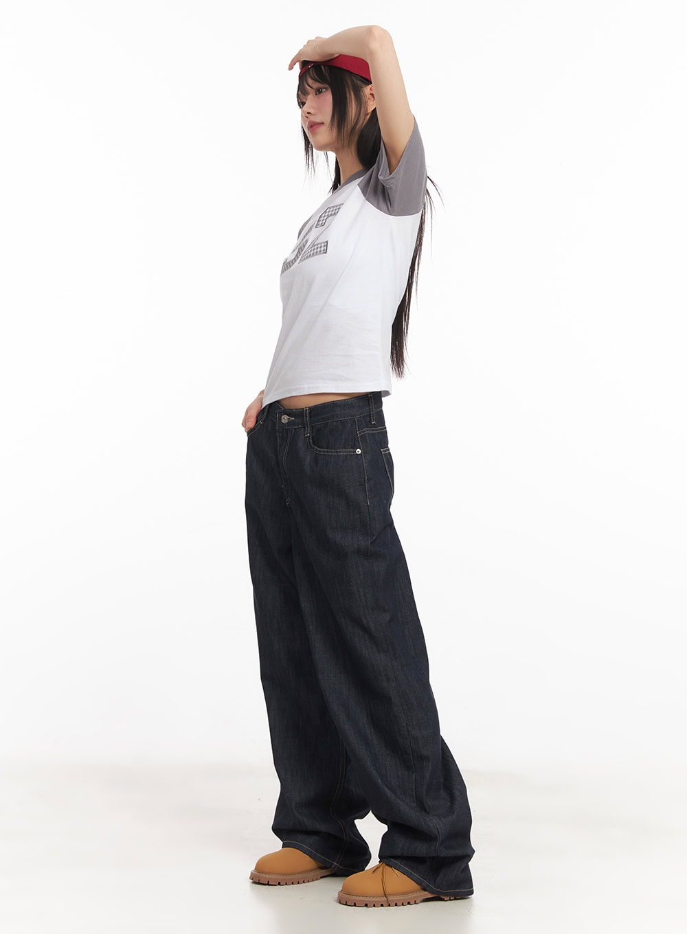 LEWKIN Ivara Wide-Leg Jeans CA522 in dark blue, side full-length view on model, low-rise wide fit cotton denim with contrast stitching, styled with a cropped graphic tee and tan boots.