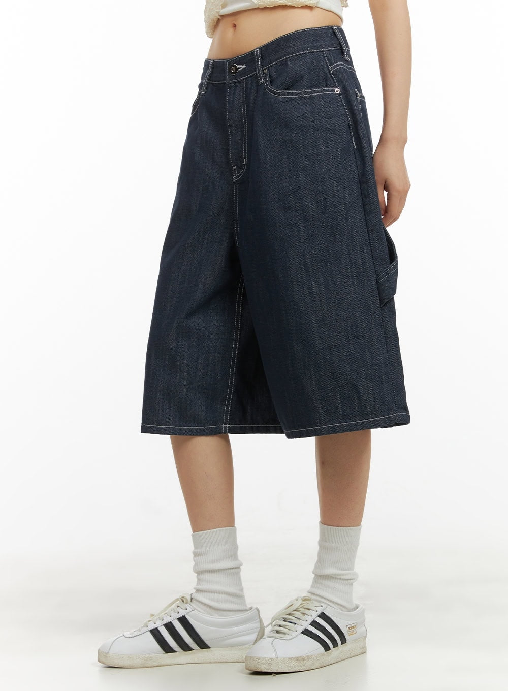 LEWKIN Solid Wide-Leg Bermuda Jorts CY414 in dark blue, side close-up on model, wide-fit midi denim with contrast white stitching and utility pocket, styled with white sneakers.