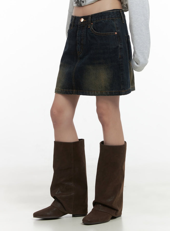 LEWKIN Washed Cotton Mini Skirt CS419 in dark blue, angled close-up on model, washed denim with golden fading, front pockets, mini length, styled with brown fold-over boots.