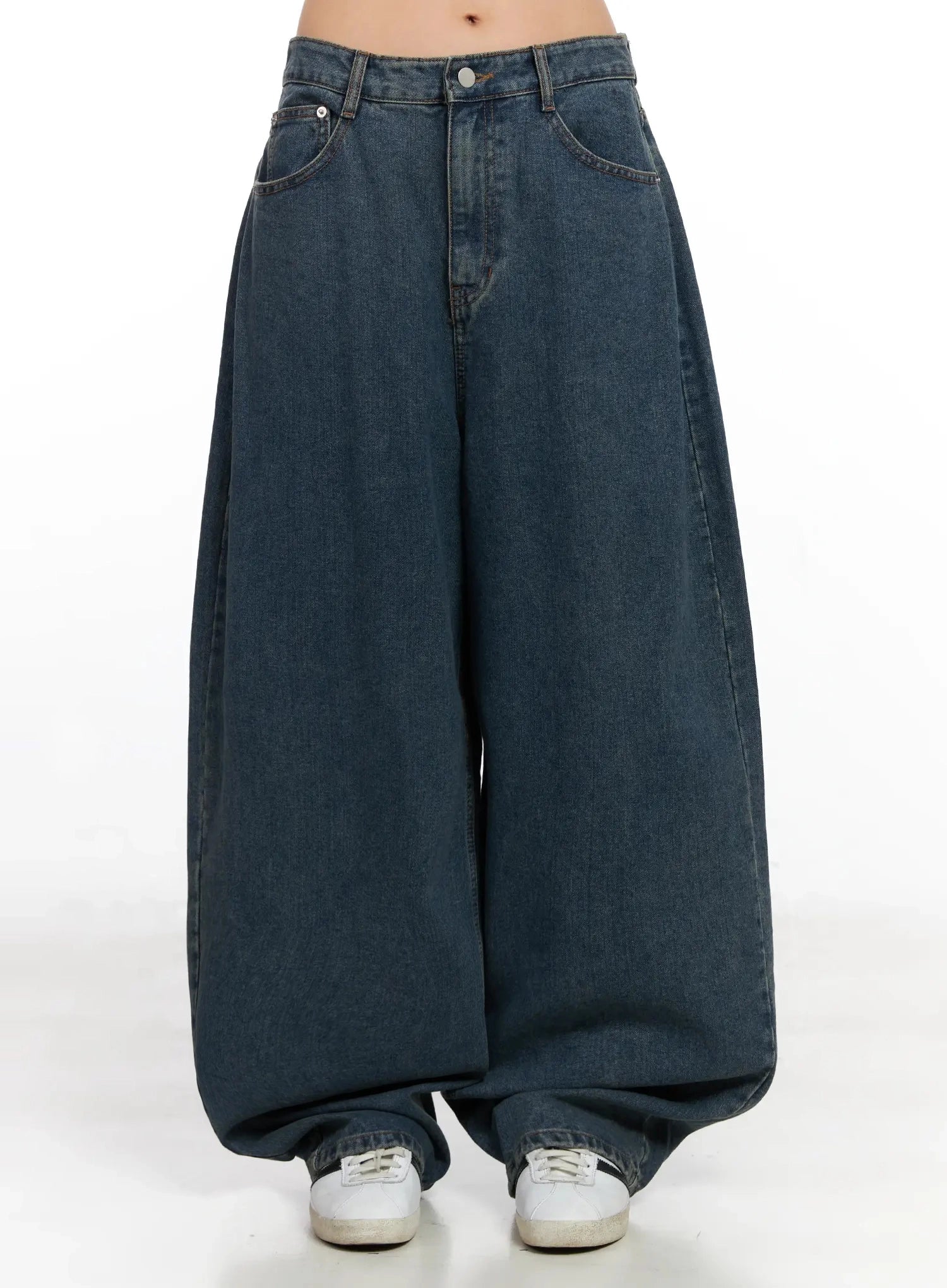 LEWKIN Aleena Mid-Wash Baggy Jeans IN528 in dark blue, front product shot on model, ultra-wide cotton denim with voluminous legs pooling at ankle, paired with white sneakers.