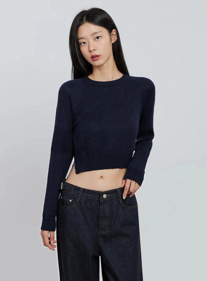 LEWKIN Side Button Cropped Knit IO530 in dark blue, front close-up on model, acrylic crew neck long sleeve crop sweater with ribbed cuffs, paired with dark wide-leg jeans.