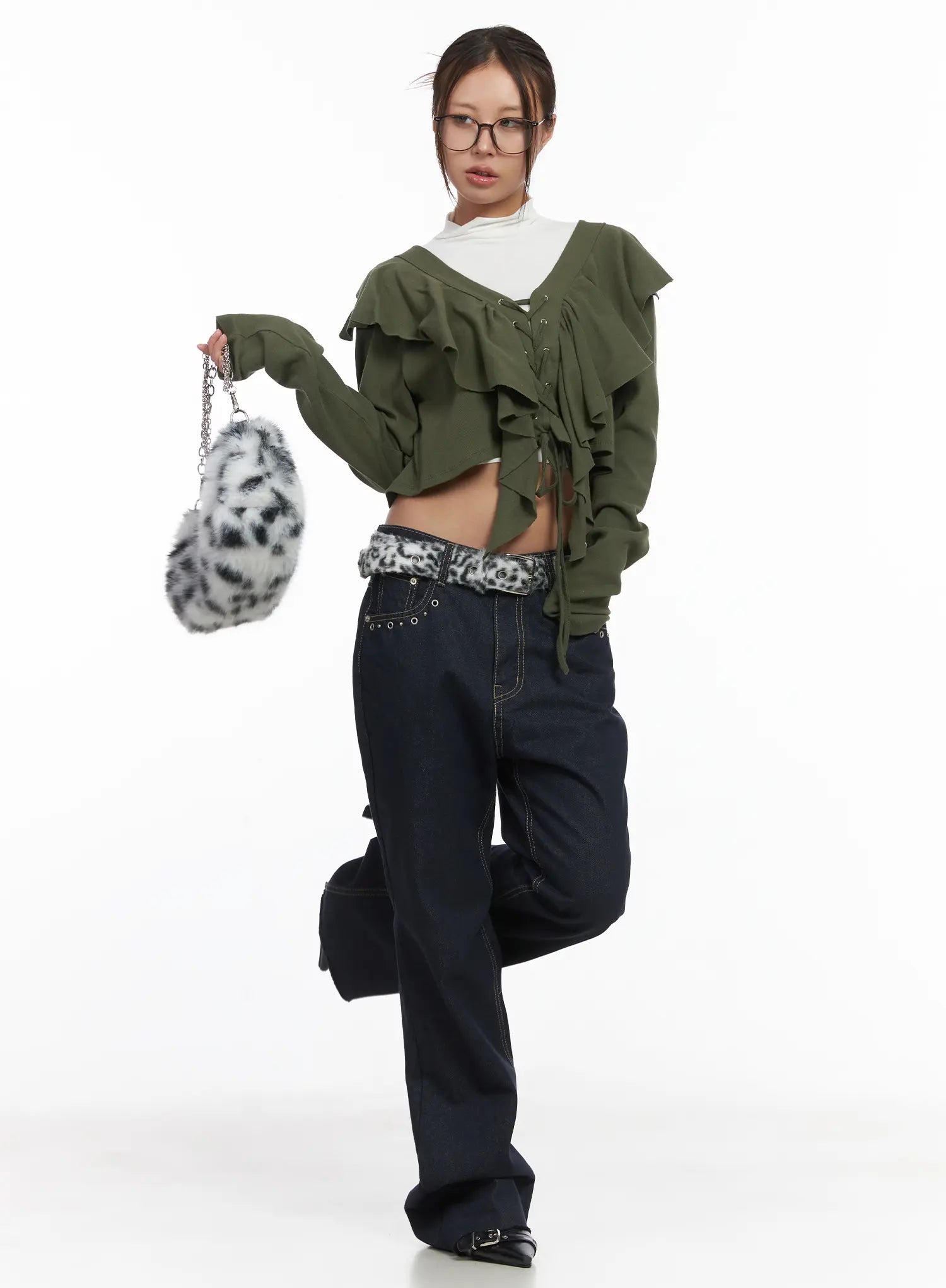 LEWKIN Bunn Non-Fade Eyelet Bootcut Jeans CJ512 in dark blue, full-body editorial shot on model with glasses, wide-fit cotton denim, paired with green ruffled crop top and leopard belt.