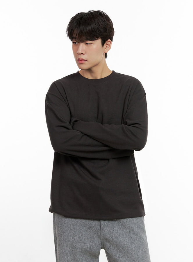 LEWKIN Men's Essential Solid T-Shirt IN422 in dark gray, front half-body on model, arms crossed, crew neck long sleeve, paired with gray wide-leg trousers.