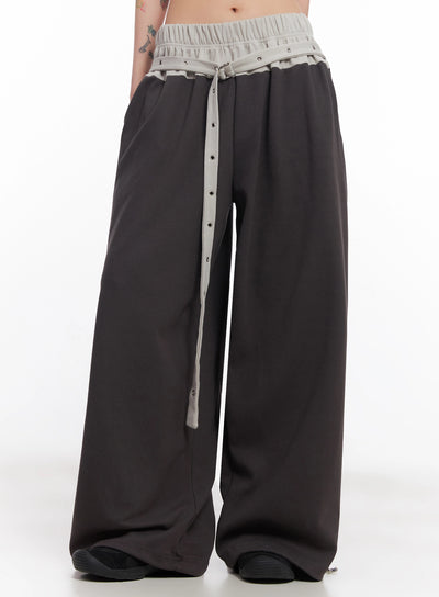 LEWKIN Eyelet Belted Trousers IC503 in dark gray, front crop view on model, wide-leg silhouette with contrast light gray ruched waistband and eyelet belt strap.