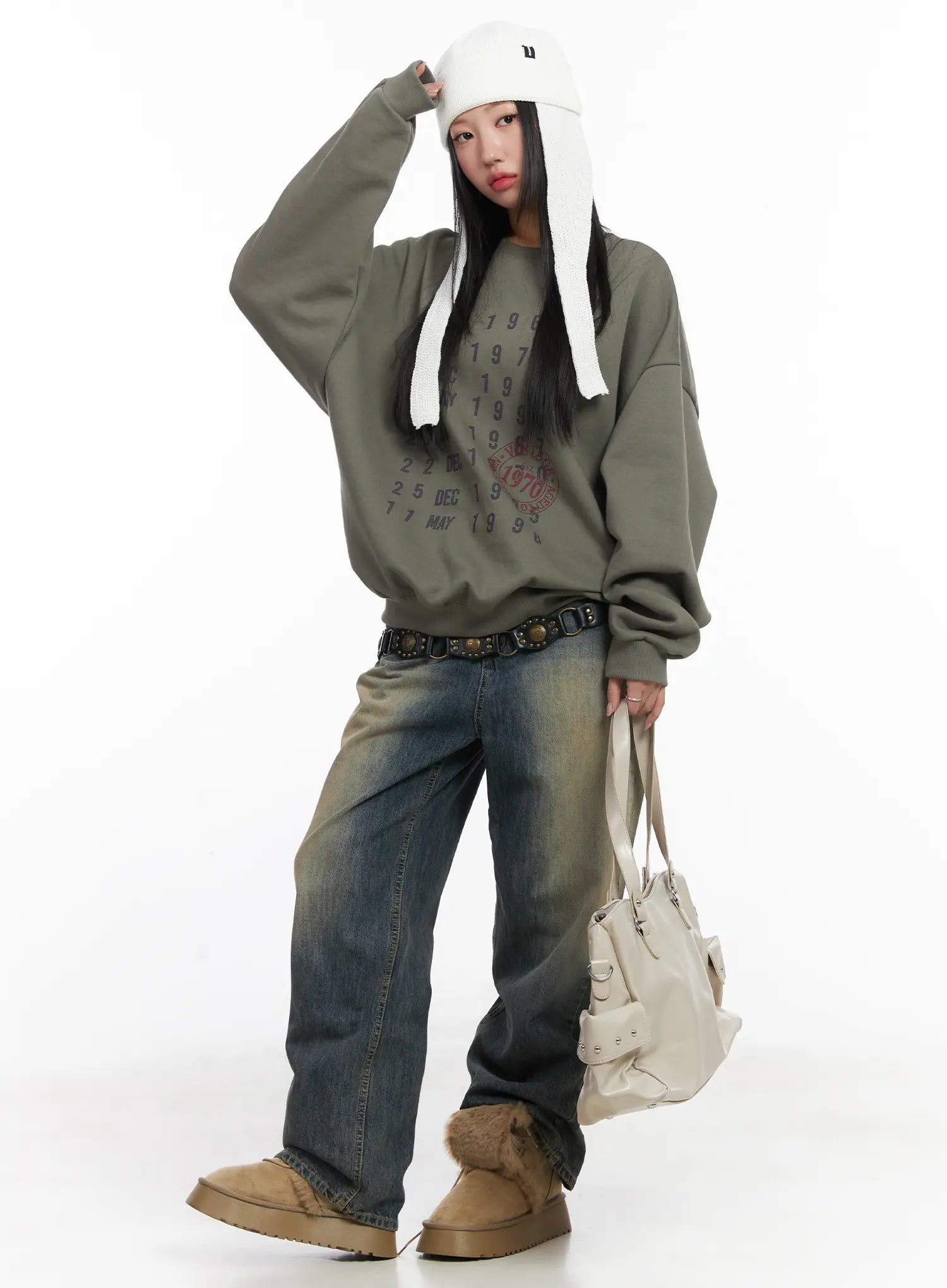 Wide Washed Jeans CS06 in vintage blue, three-quarter front shot on model, wide-leg sandy-wash cotton denim with belt, layered under olive crewneck sweatshirt, fluffy boots, trapper hat.
