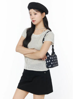 LEWKIN Sheer Short Sleeve Top and Scarf CY522 in light beige, three-quarter front view on model, sheer linen-blend knit with scarf choker detail, paired with black mini skirt and polka-dot bag.