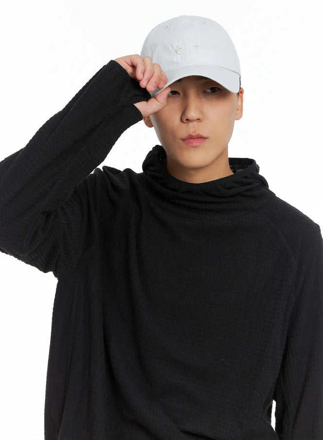 LEWKIN Men's Embroidered Baseball Cap IS502 in light gray, close-up front on model tilting brim with hand, tonal embroidered logo on crown, paired with black waffle-knit hoodie.
