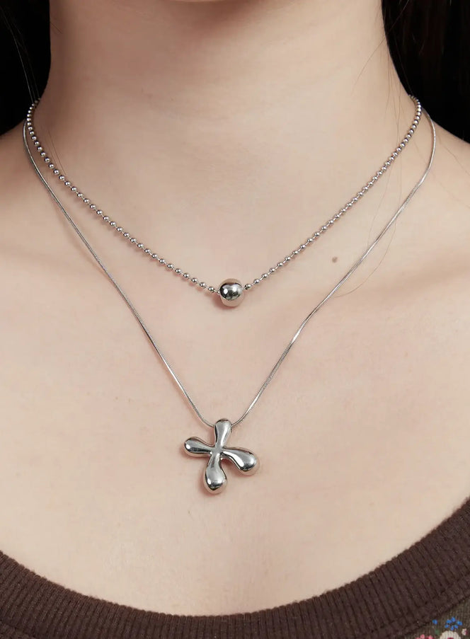 LEWKIN Layered Boomerang Necklace ID529 in silver, close-up on model's neck, double-layer ball chain choker and snake chain with puffy boomerang pendant, worn over brown tank top.