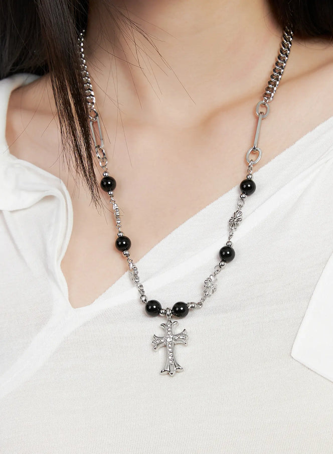 LEWKIN Gothic Cross Pendant Necklace CG526 in silver, close-up on model's neckline, ornate cross pendant with crystal inlay, black onyx beads, mixed curb and paperclip chain, styled over white V-neck top.