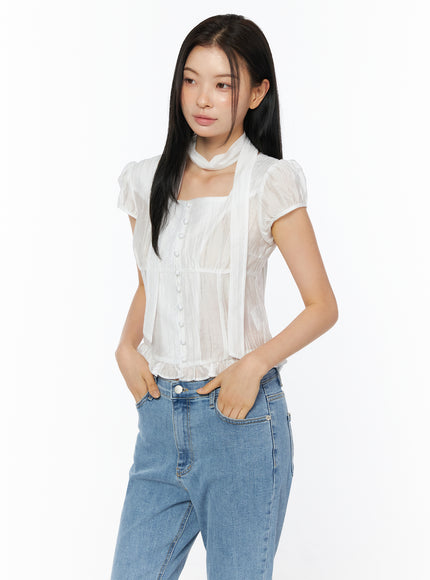 LEWKIN Puff Sleeve Shirred Blouse with Scarf IU519 in white, 3/4 front view on model, sheer nylon-tencel square neck with center button placket, ruffled hem and scarf, styled with blue jeans.