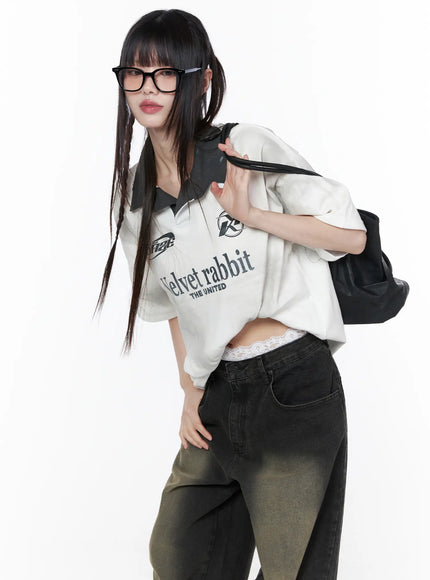LEWKIN Oversized Collar Jersey CU519 in white, three-quarter front on model leaning forward, oversized sporty jersey with dark contrast collar and graphic print, paired with dark wide-leg jeans and black bag.
