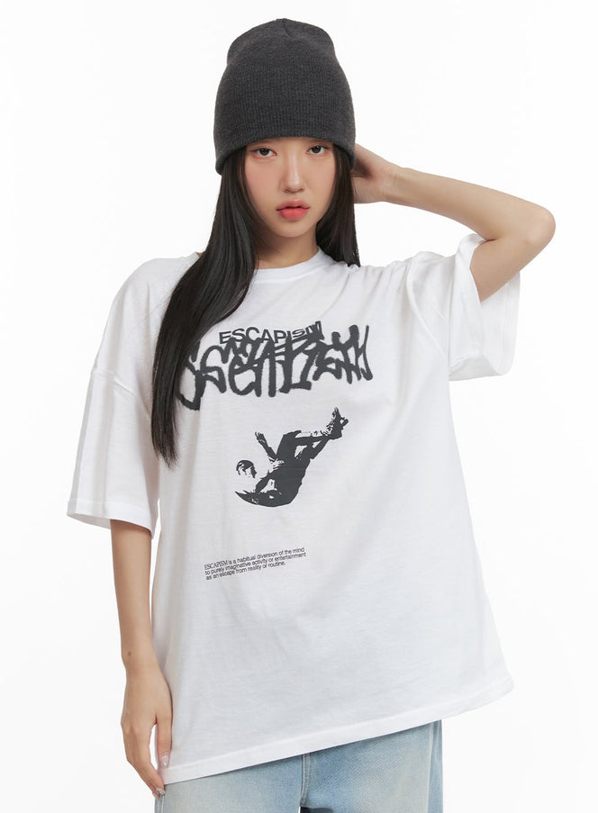 LEWKIN Graphic Oversized T-Shirt CY423 in white, front crop shot on model, black graffiti ESCAPISM lettering and falling figure print on cotton, styled with gray beanie.