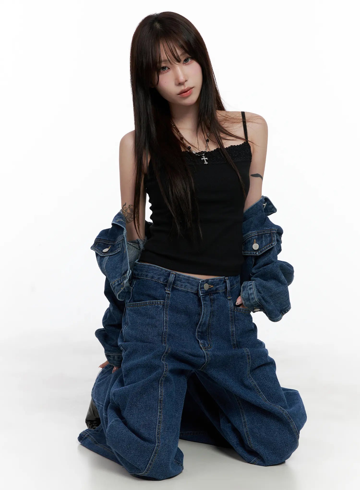 LEWKIN Eliza Seam Detail Relaxed Bootcut Jeans CO521 in washed blue, full-body editorial shot, model kneeling in black cami top and denim jacket, loose cotton bootcut silhouette.