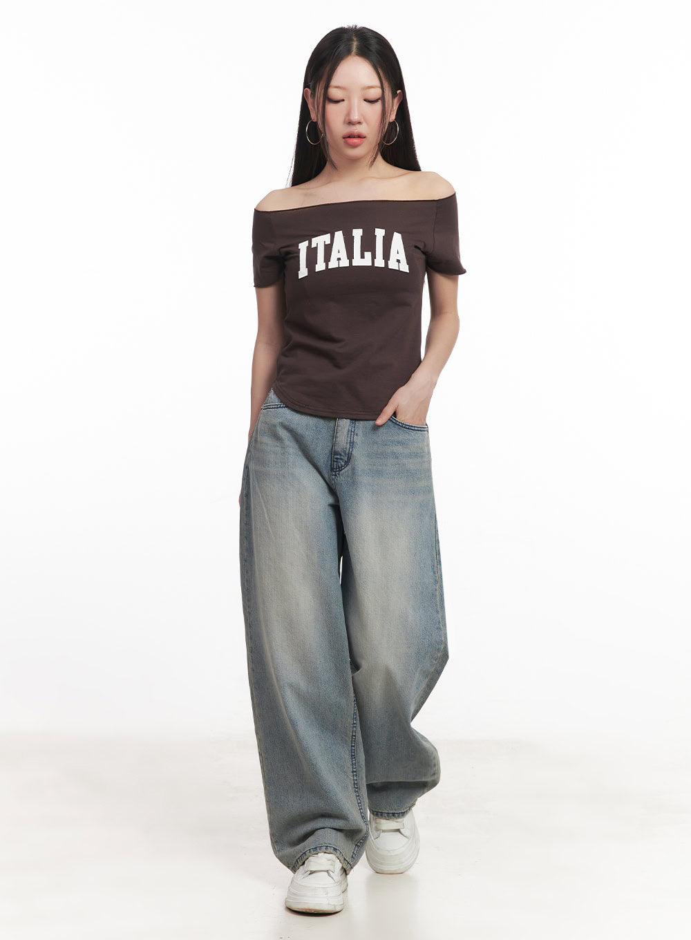 LEWKIN Casey Washed Baggy Jeans IM528 in light blue, full-length front view on model looking down, wide-fit washed denim pooling at hem, paired with brown off-shoulder crop top and white sneakers.