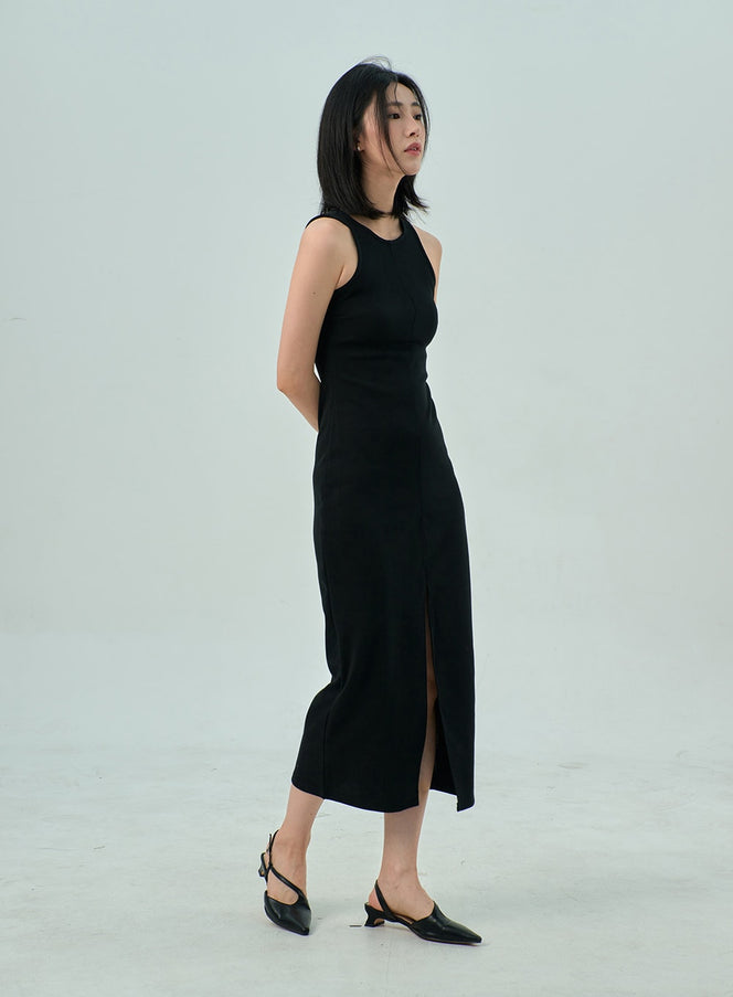 LEWKIN Slit Sleeveless Maxi Dress OY310 in black, side view on model, slim-fit maxi length with front slit, round neck, center seam detail, styled with black slingback heels.